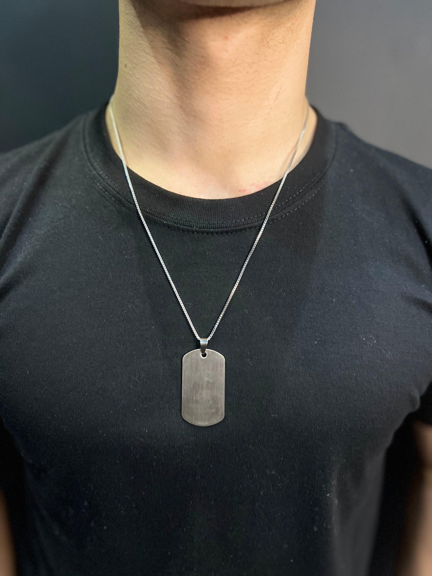 silver dog tag pendant , black shirt , front side
